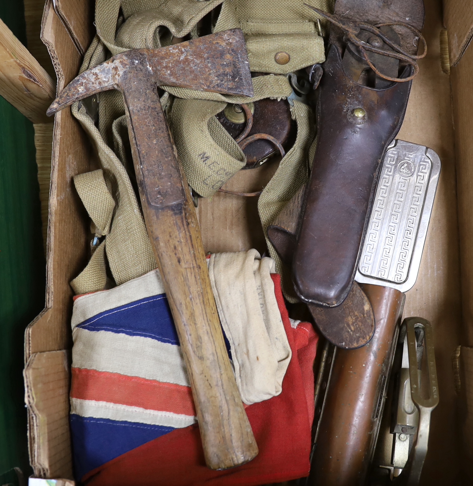 A collection of militaria including a union flag, gunners sight, camouflage webbing, a water bottle, an axe, a bosun’s whistle, and other items